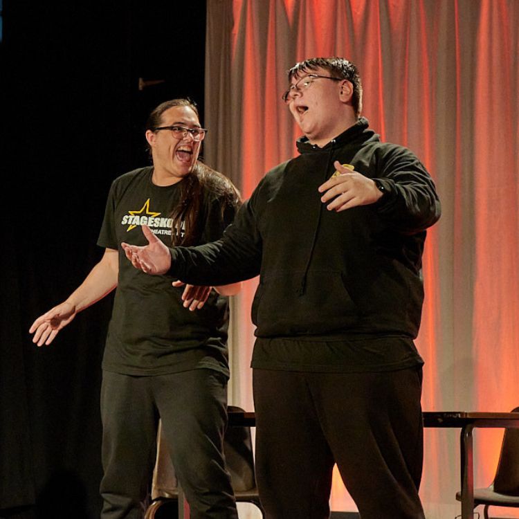 Two teenage students acting, singing and dancing on stage.